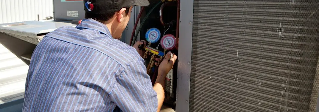 HVAC technician servicing a condenser unit in East Goshen